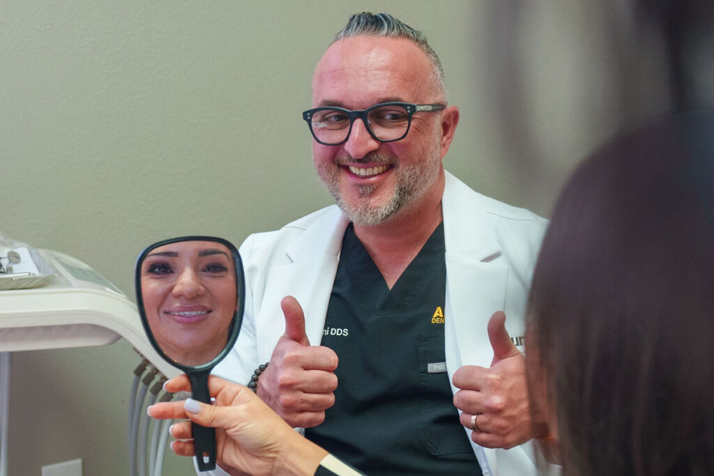 Dr. Baha Duraini giving a thumbs up as a smiling patient looks at her new smile in a hand mirror